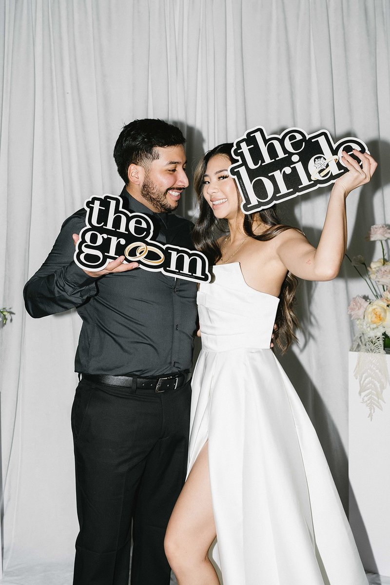 A couple with bride and groom props at the Icon booth