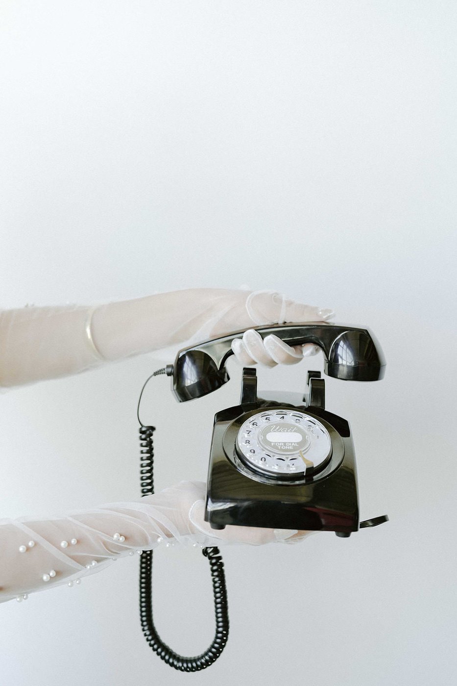 A white-gloved hand holding the black vintage rotary phone of the audio guestbook