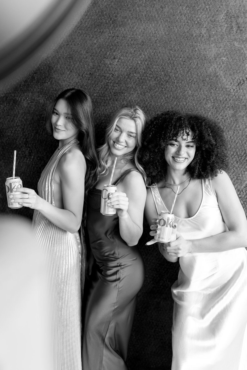 Three friends laughing with drinks at a holiday party, in black and white