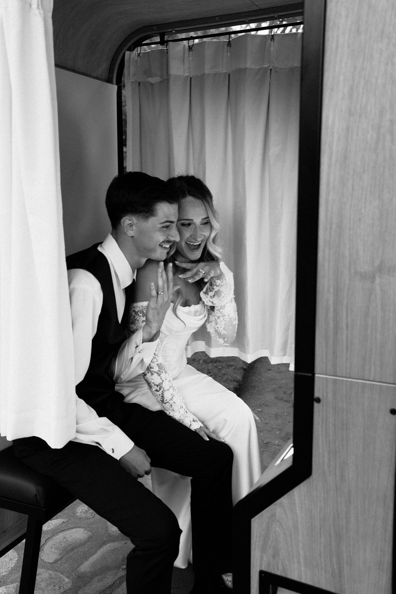 A couple laughing together inside the enclosed vintage photo booth, in black and white