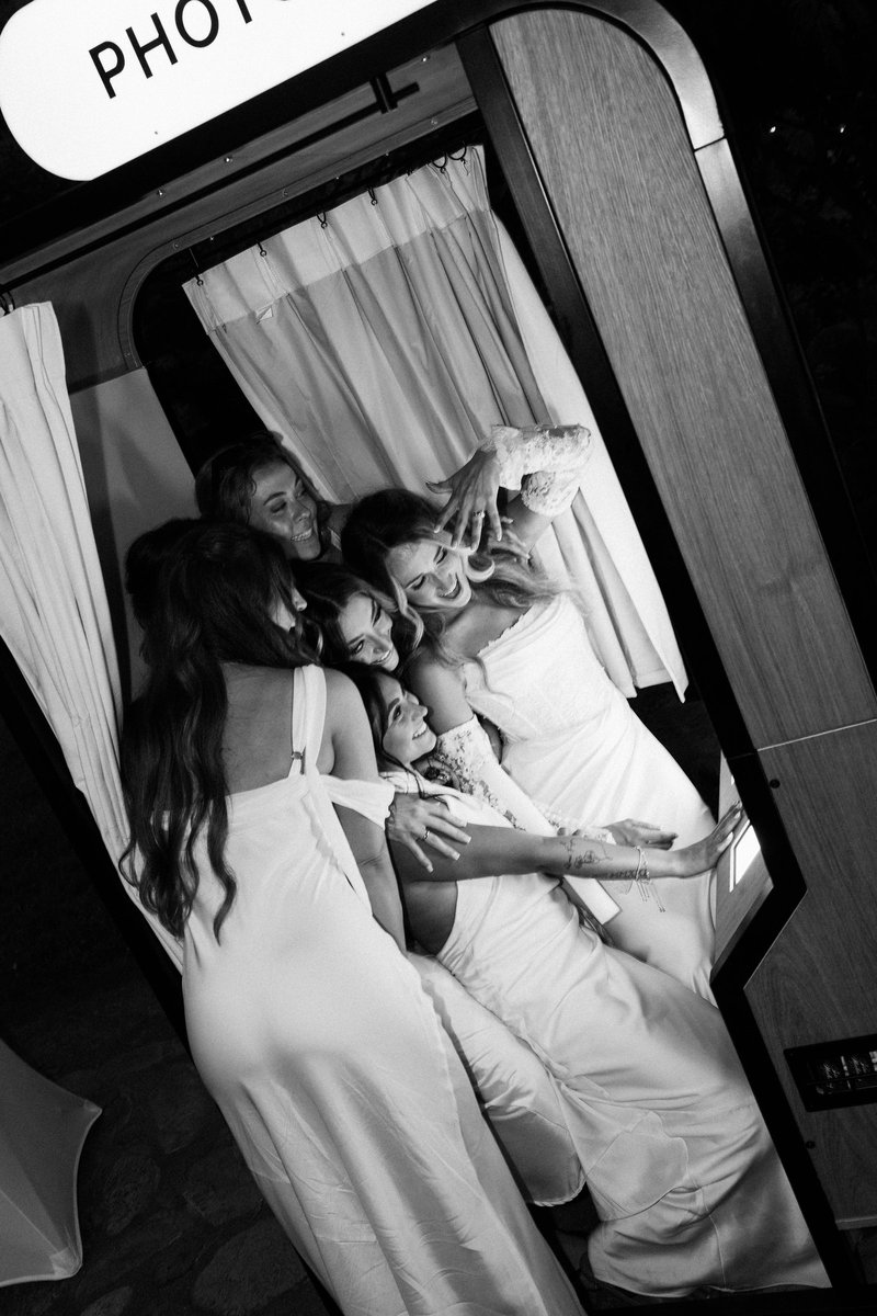 Wedding guests crowded inside the enclosed photo booth, in black and white