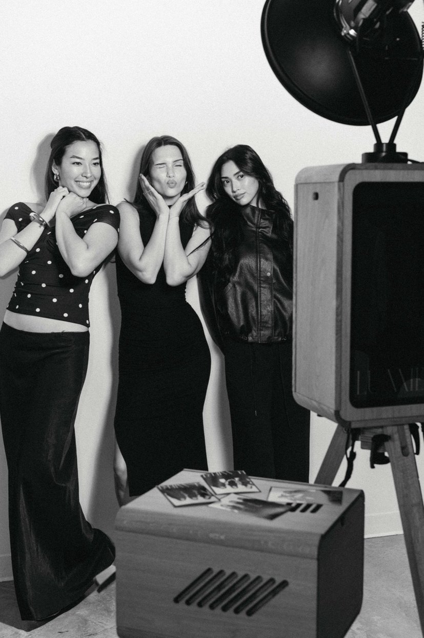 Three guests posing beside the open-air booth, in black and white