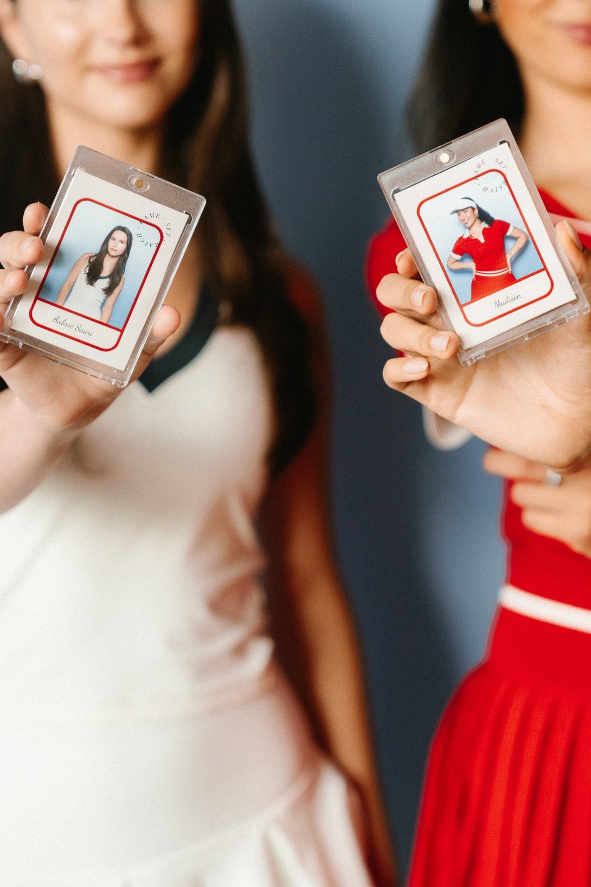Two guests holding up custom trading card prints of themselves