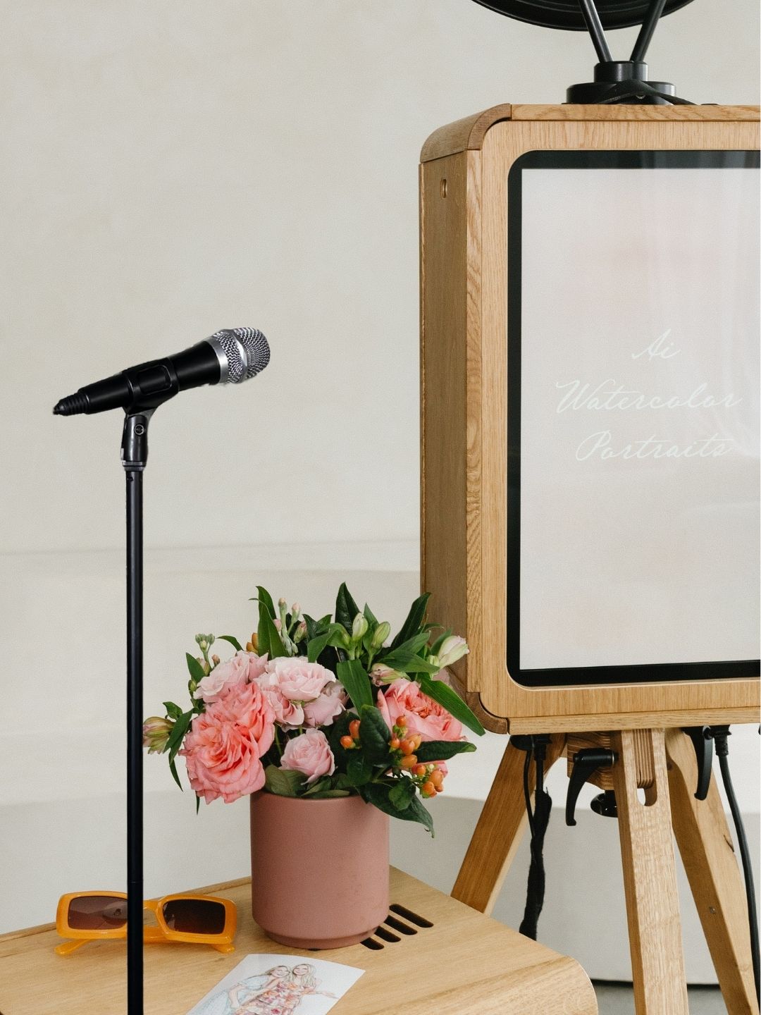 The video guestbook setup: a microphone on a stand beside the booth and a vase of flowers