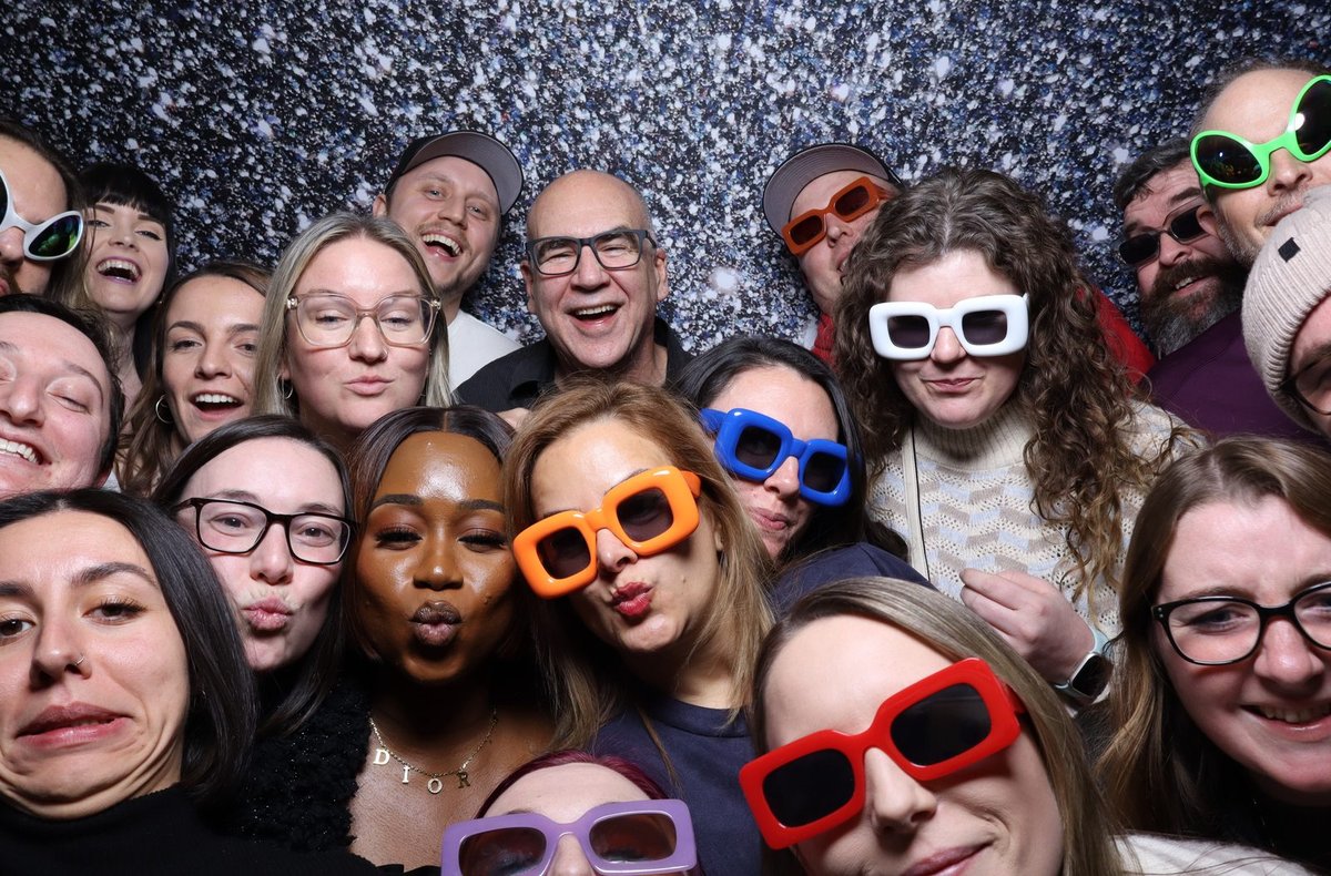 A team packed into frame wearing party glasses