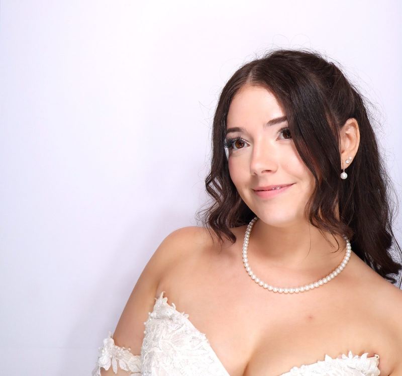 A bride in pearls smiling over her shoulder in the booth