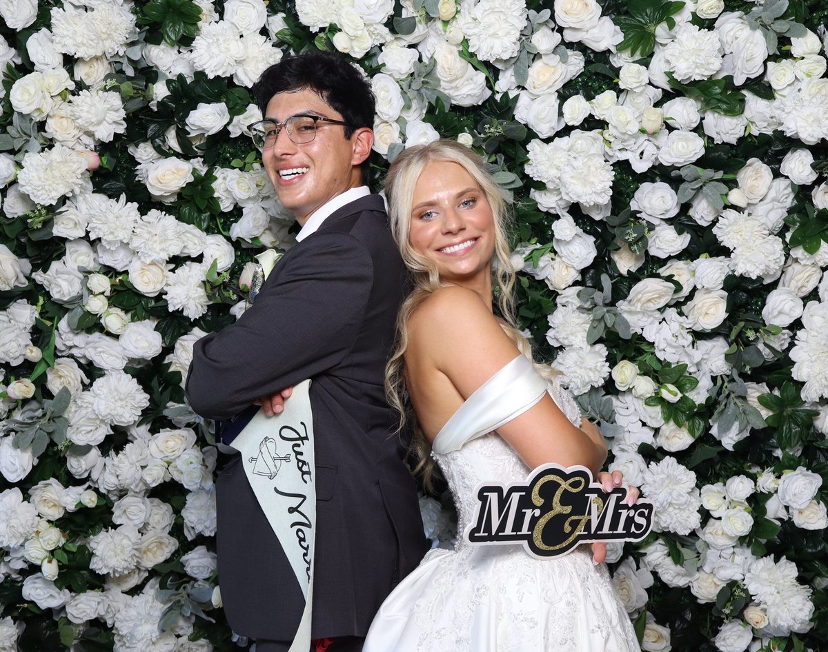 A couple with a Mr and Mrs sign at the flower wall