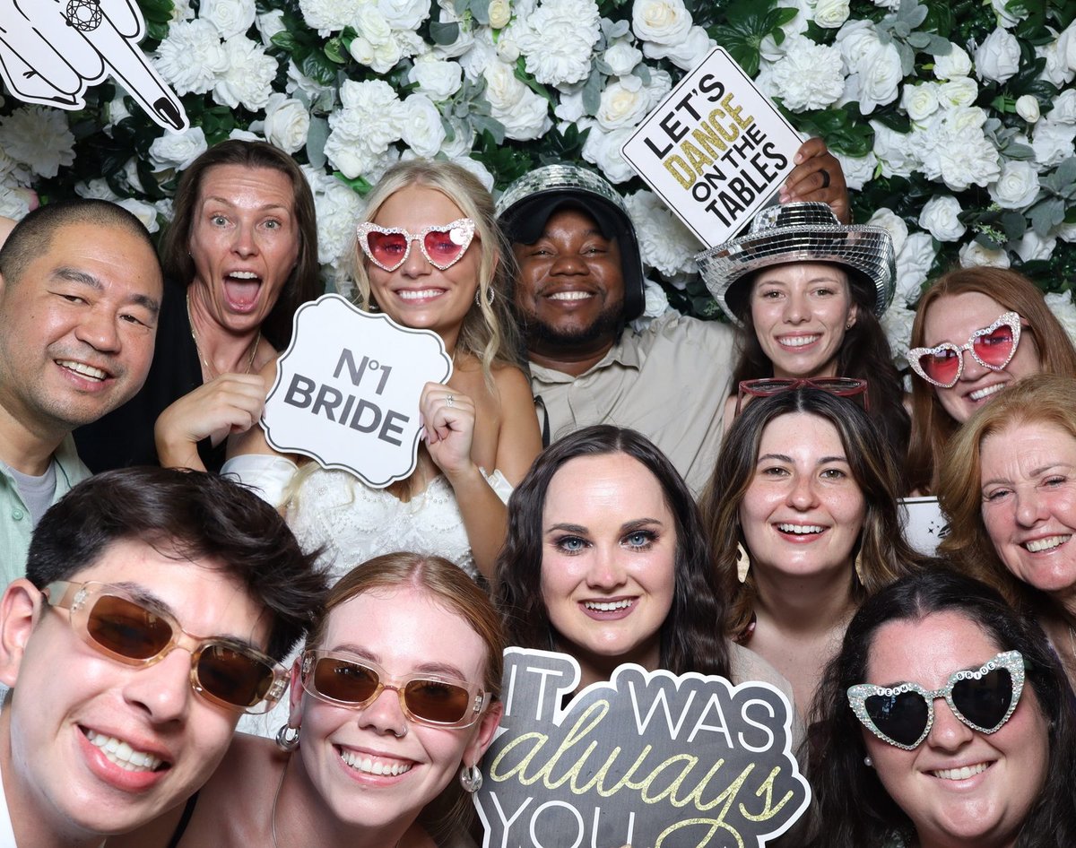 The glam squad crowding the booth with heart sunglasses