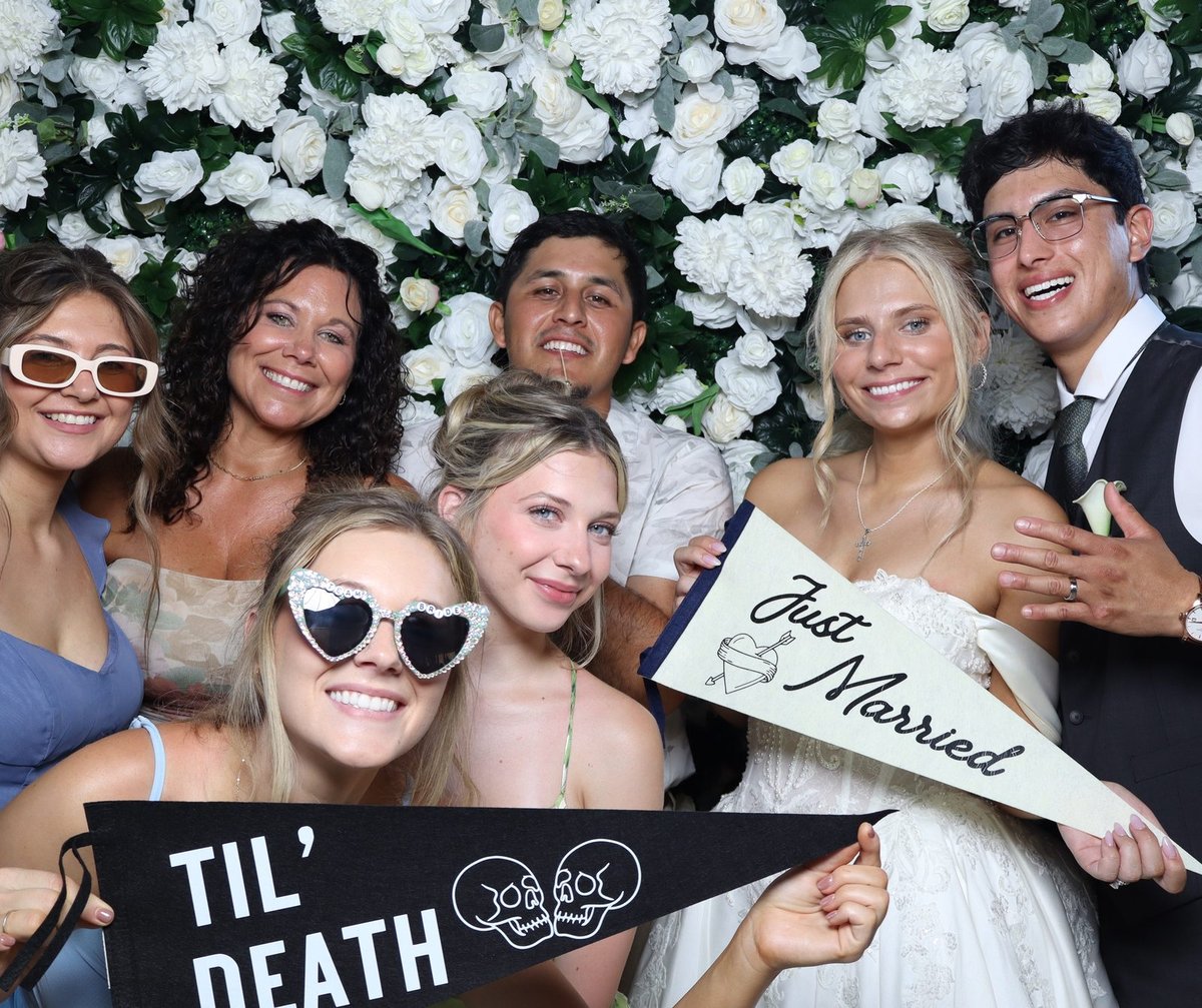 Wedding guests in sunglasses holding a just married pennant