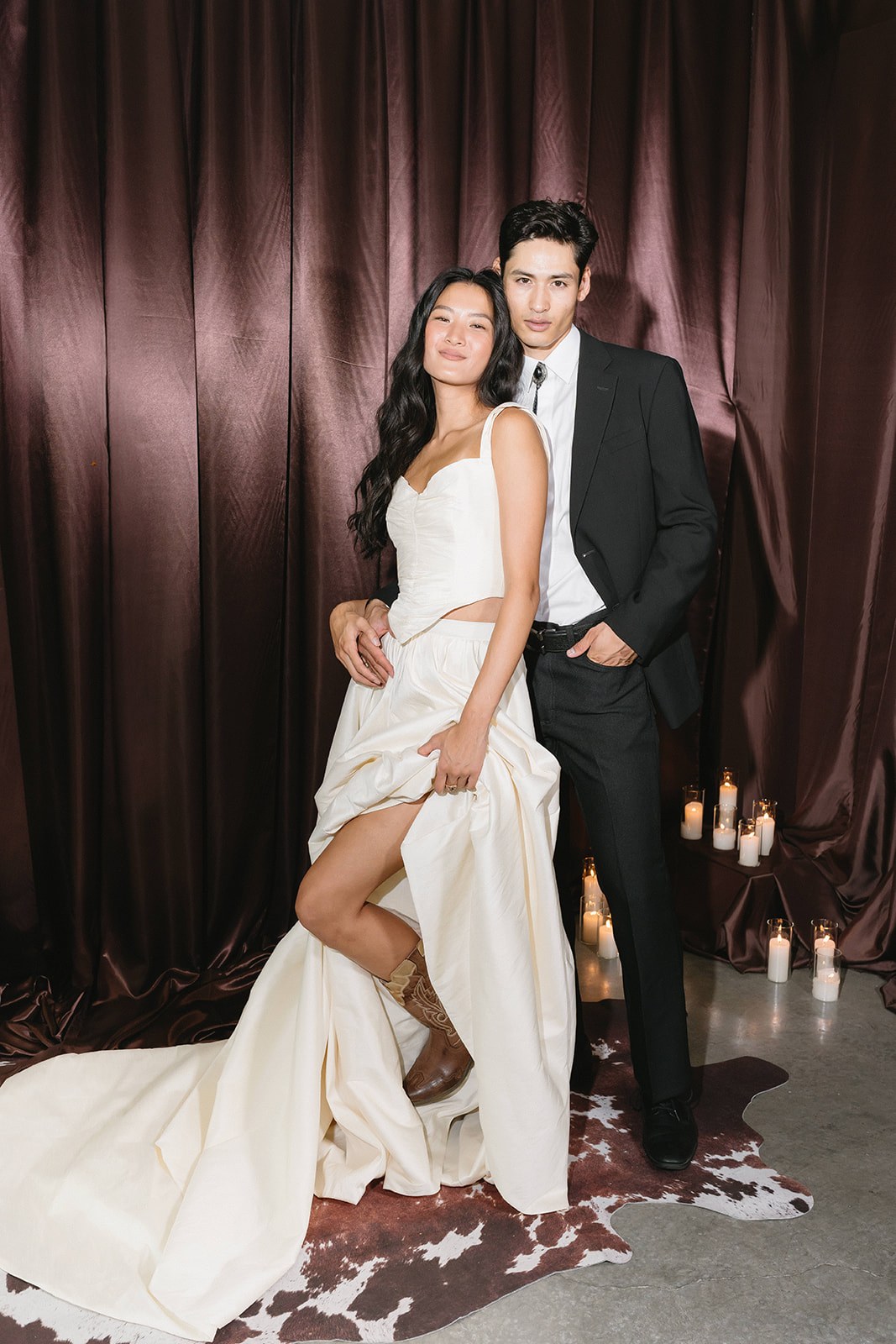 A bride and groom posing in front of a brown drape in the portrait lounge