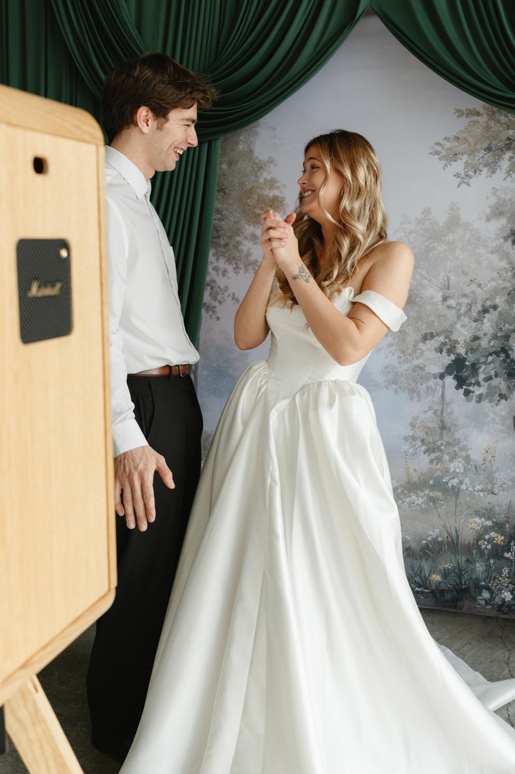 A bride and groom posing beside the booth in front of the forest backdrop