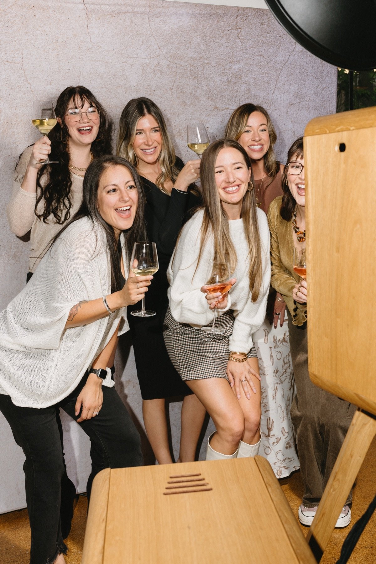 Friends toasting with wine glasses beside the open-air booth at a party
